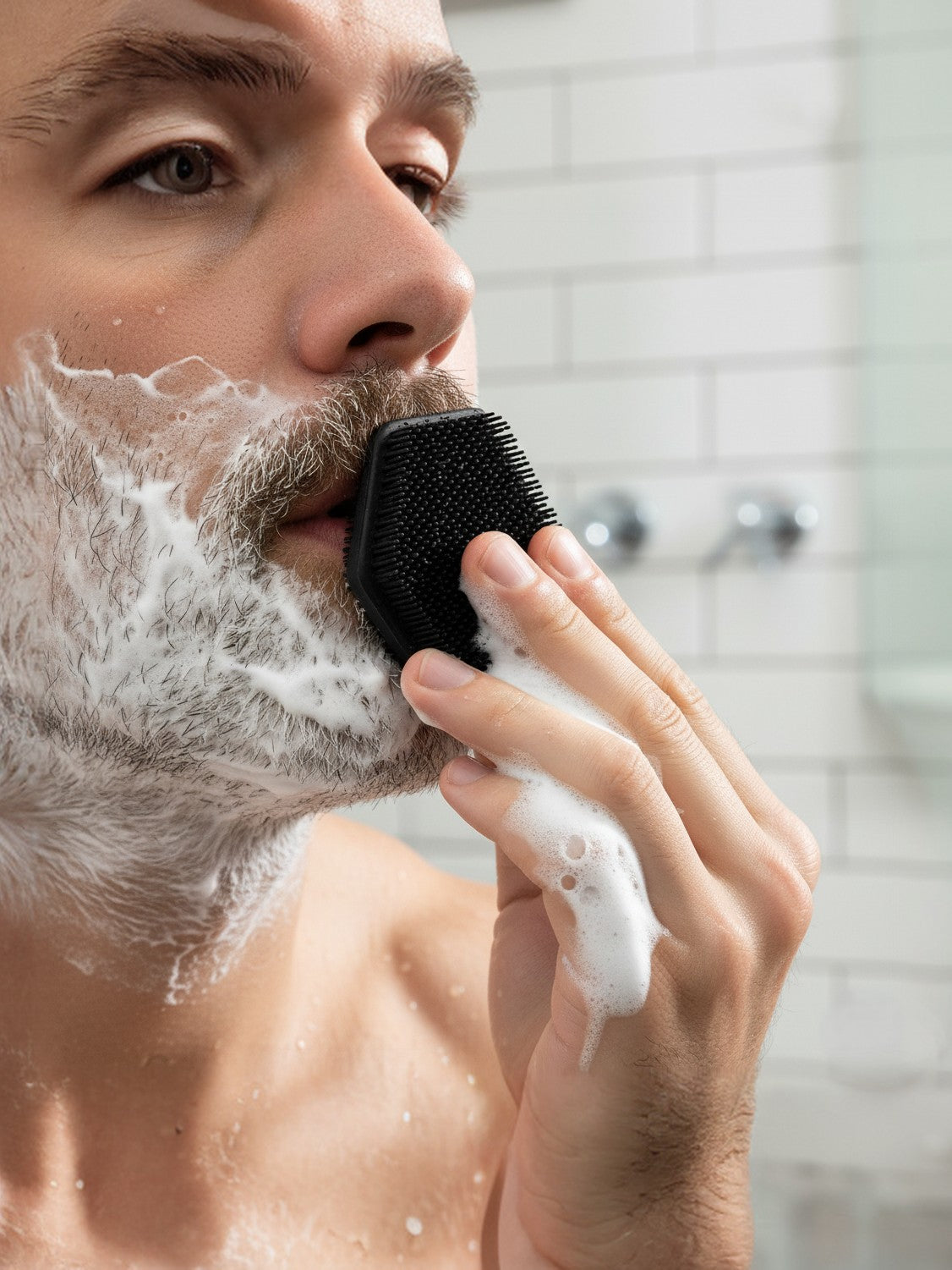 Man shaving with a brush and foam in a bathroom setting