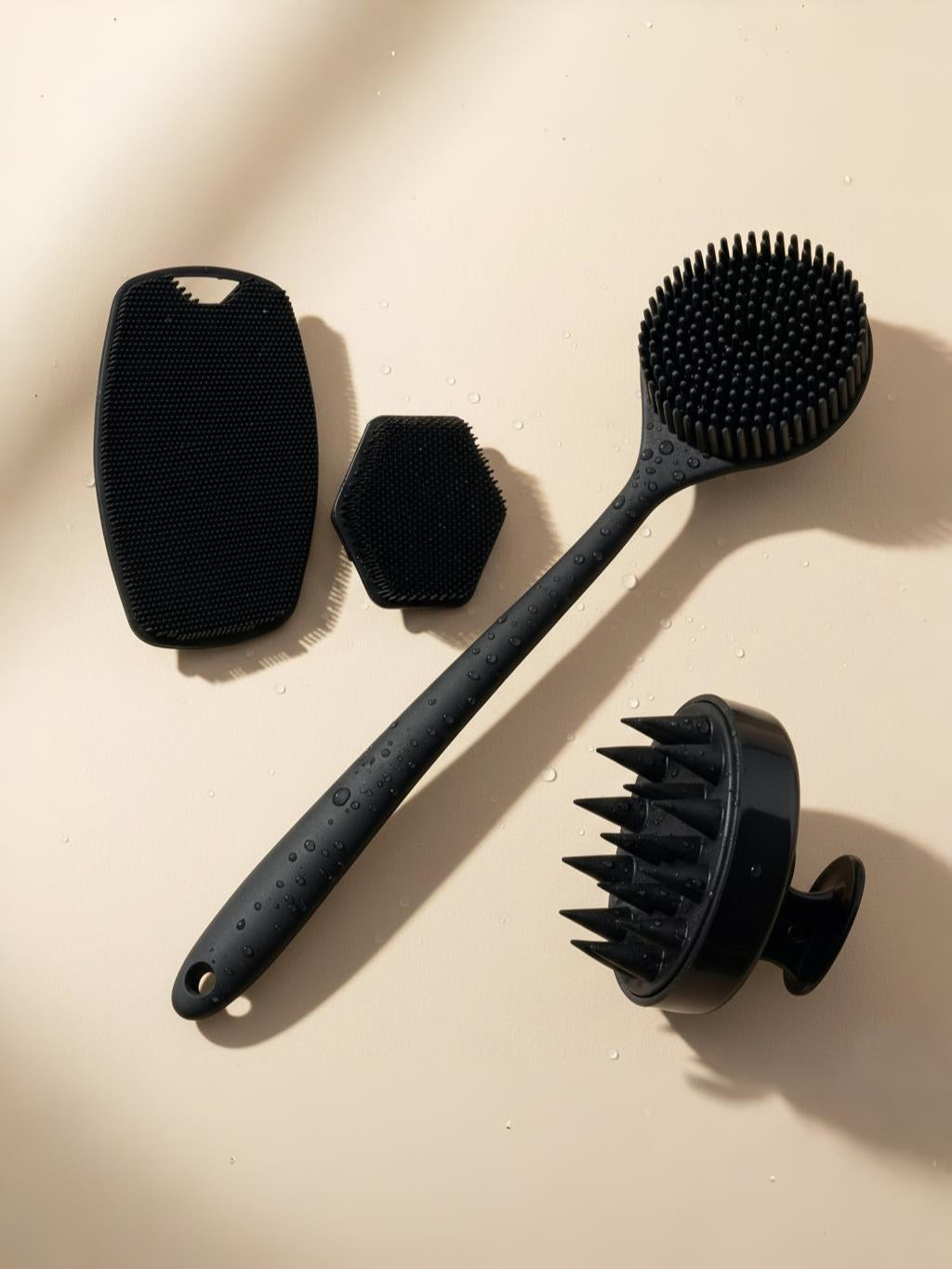Set of black massage brushes on a beige background